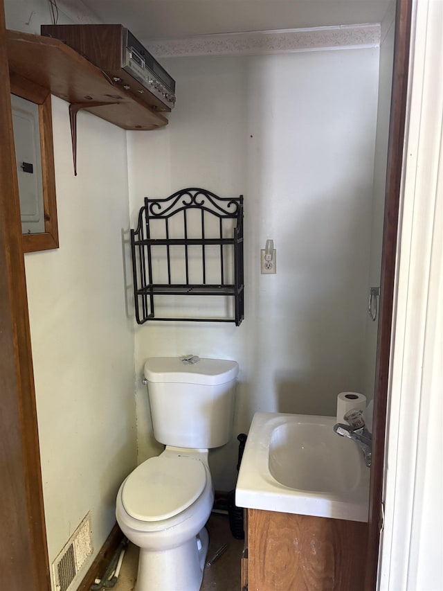 half bath with toilet, vanity, visible vents, and electric panel