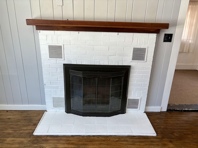 details with a glass covered fireplace, visible vents, and wood finished floors