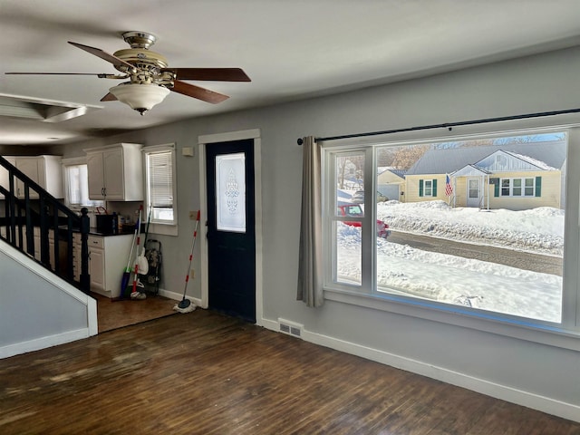 entryway featuring dark wood-type flooring, a ceiling fan, visible vents, baseboards, and stairway