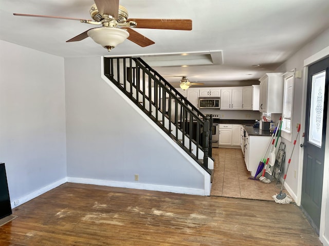 kitchen featuring baseboards, dark countertops, light wood-style flooring, stainless steel appliances, and white cabinetry