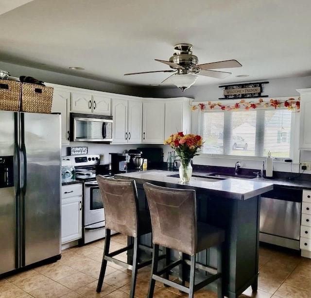 kitchen featuring white cabinets, a breakfast bar, stainless steel appliances, a sink, and light tile patterned flooring