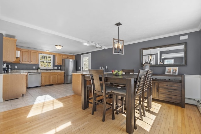 dining area with ornamental molding, a chandelier, and light wood-style flooring