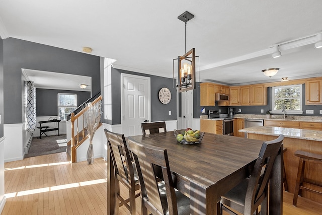 dining room with light wood-style floors, stairs, crown molding, and rail lighting