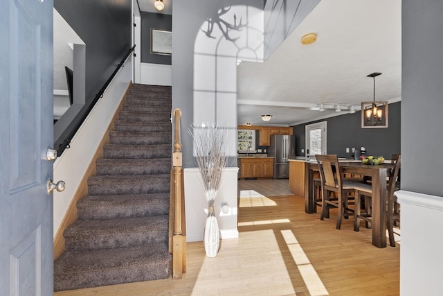 stairs featuring a chandelier and wood finished floors