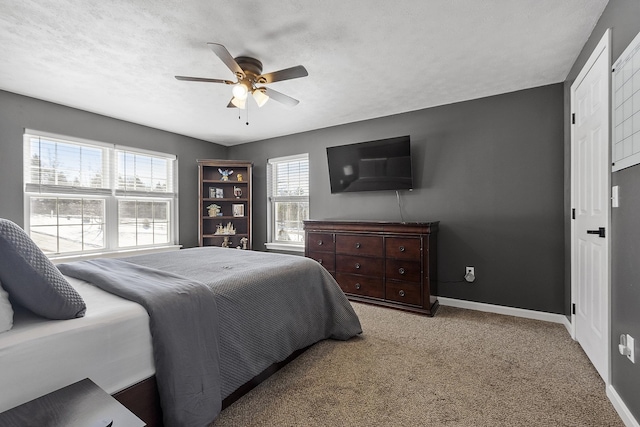 carpeted bedroom with ceiling fan, baseboards, and a textured ceiling