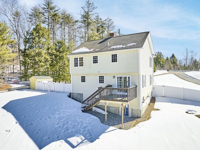 snow covered rear of property featuring a chimney, a gate, a fenced backyard, and a deck