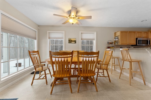 dining area with ceiling fan, a textured ceiling, baseboards, and light tile patterned floors