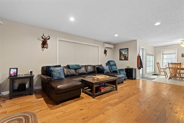 living area featuring ceiling fan, light wood-style flooring, recessed lighting, baseboards, and an AC wall unit