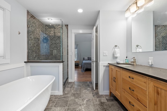 full bathroom with a soaking tub, a stall shower, wainscoting, vanity, and ensuite bath