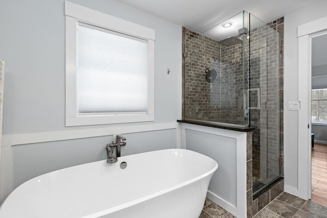 full bathroom with a wainscoted wall, a freestanding tub, a shower stall, and a decorative wall