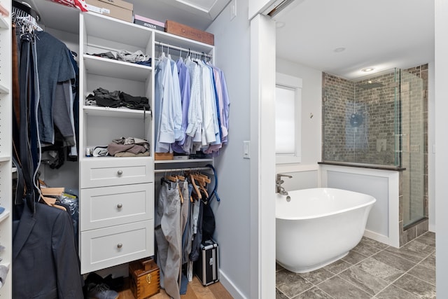 full bathroom with a freestanding bath, a shower stall, and a walk in closet