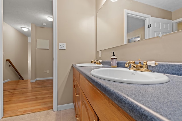 bathroom with double vanity, a sink, baseboards, and tile patterned floors