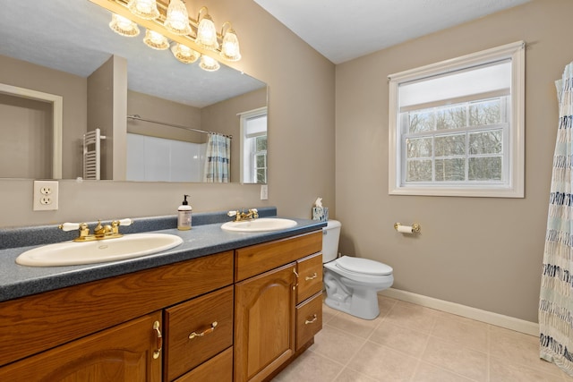 bathroom with double vanity, a sink, baseboards, and tile patterned floors