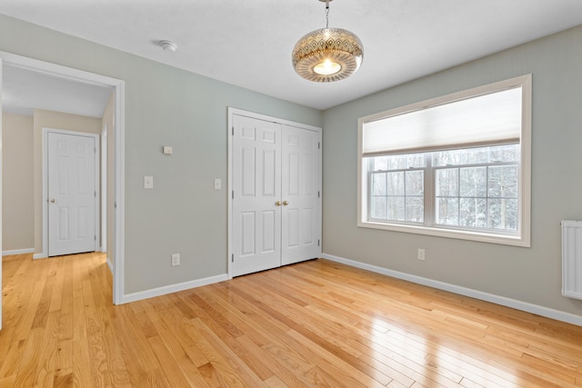 unfurnished bedroom with light wood-type flooring, a closet, and baseboards