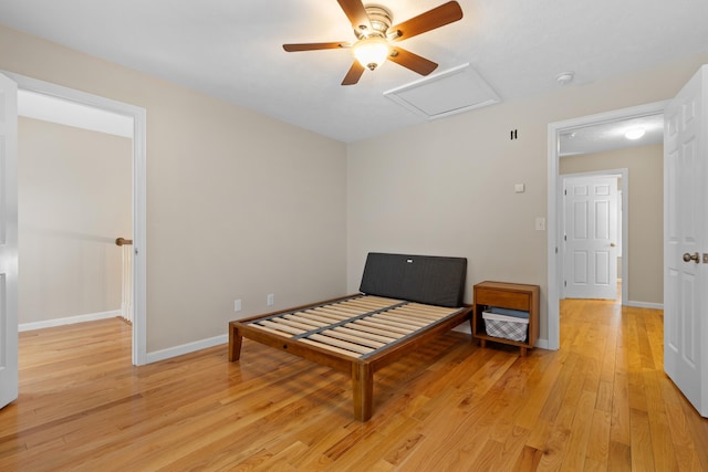 sitting room featuring attic access, light wood-type flooring, baseboards, and a ceiling fan