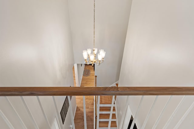 staircase featuring an inviting chandelier and wood finished floors