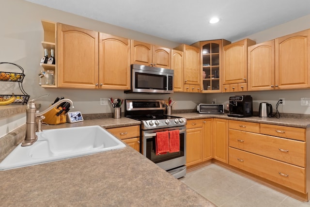 kitchen with stainless steel appliances, recessed lighting, glass insert cabinets, light brown cabinets, and a sink