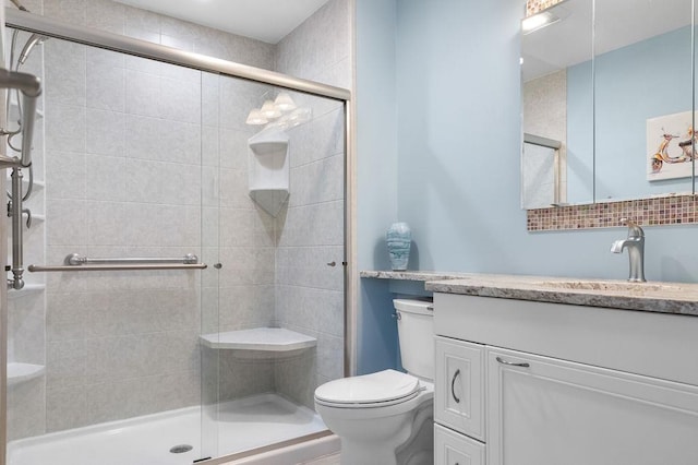 bathroom with vanity, a shower stall, and toilet