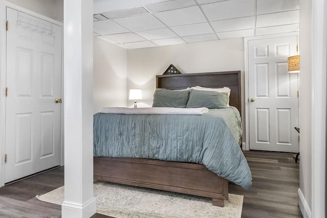 bedroom with a drop ceiling and wood finished floors