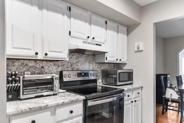 kitchen with appliances with stainless steel finishes, a toaster, white cabinets, and under cabinet range hood