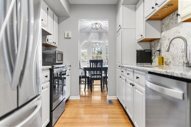 kitchen featuring light wood finished floors, appliances with stainless steel finishes, and white cabinets