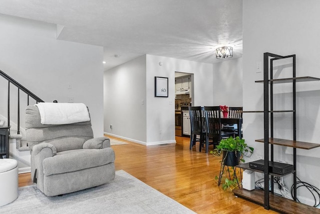 living area featuring stairway, wood finished floors, and baseboards