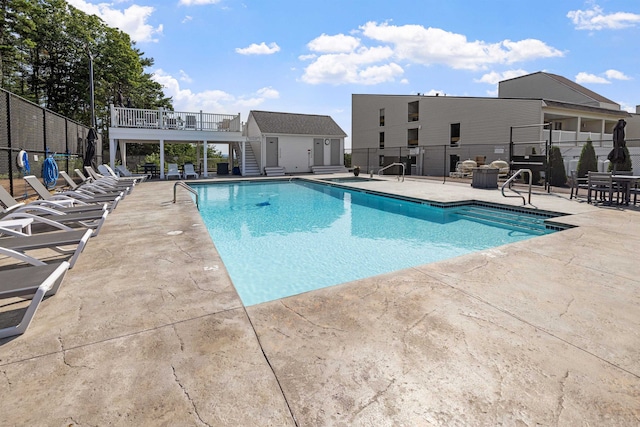 community pool with an outbuilding, stairway, a patio area, and fence