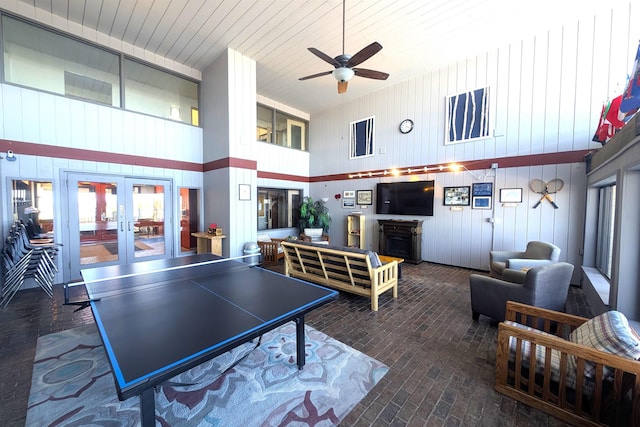 playroom featuring ceiling fan, french doors, a fireplace, wooden ceiling, and brick floor