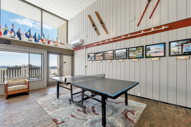 rec room with french doors, an AC wall unit, brick floor, and a towering ceiling