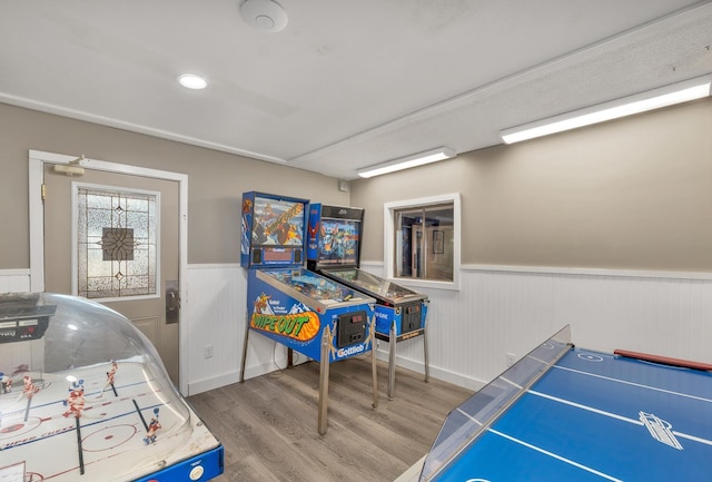 game room with wood finished floors and a wainscoted wall