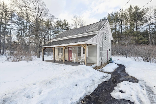 view of front of property featuring covered porch, metal roof, and a chimney