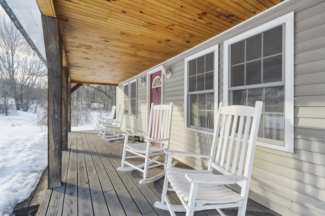 snow covered deck featuring a porch