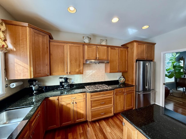 kitchen with stainless steel appliances, light wood-type flooring, brown cabinets, and under cabinet range hood