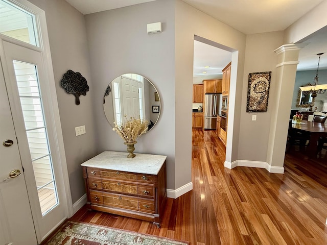 foyer entrance featuring ornate columns, baseboards, and dark wood-style flooring