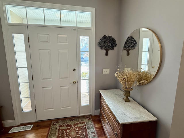 foyer featuring dark wood-style flooring, visible vents, and baseboards