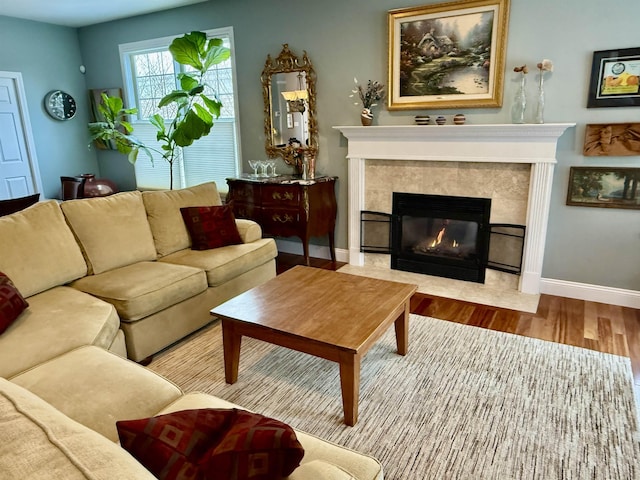 living area with baseboards, a tiled fireplace, and wood finished floors