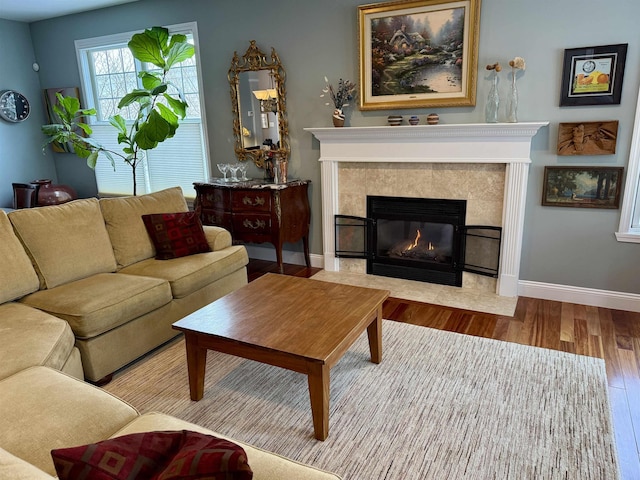 living area featuring baseboards, a tiled fireplace, and wood finished floors