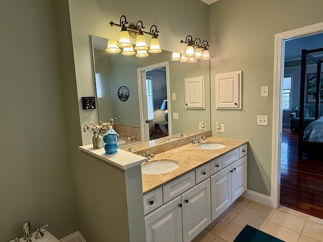 bathroom featuring tile patterned flooring, double vanity, a sink, and ensuite bathroom