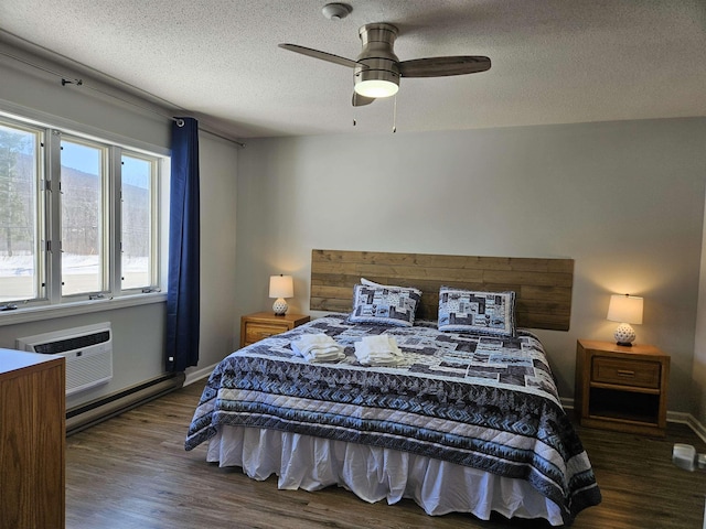 bedroom with a wall unit AC, a baseboard radiator, a textured ceiling, and wood finished floors