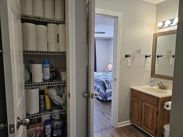 bathroom with ensuite bath, a textured ceiling, wood finished floors, and vanity