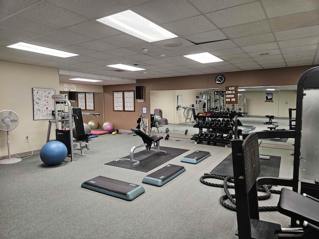 workout area featuring visible vents, a paneled ceiling, and baseboards