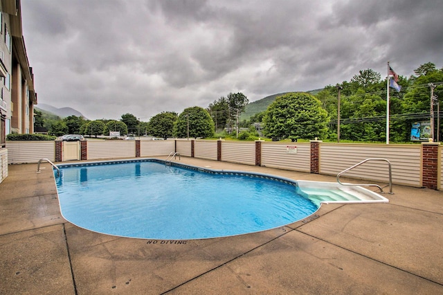 view of swimming pool featuring a mountain view, a patio area, fence, and a fenced in pool