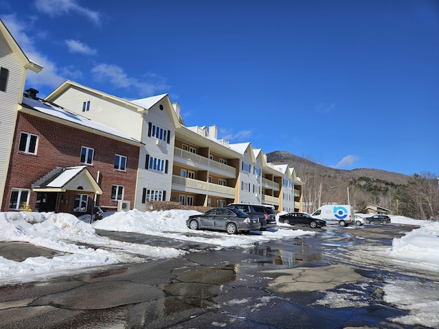 snow covered building with uncovered parking and a mountain view