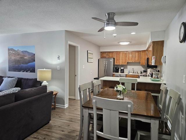 dining area featuring baseboards, a textured ceiling, a ceiling fan, and dark wood-style flooring