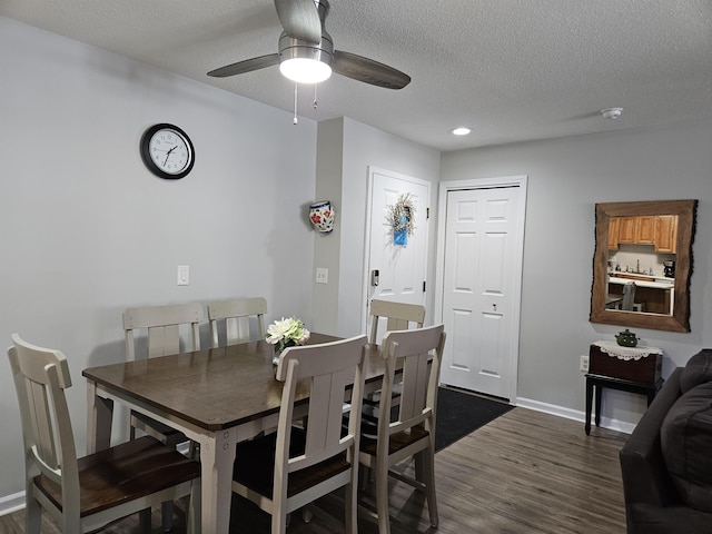 dining space featuring dark wood-style floors, ceiling fan, a textured ceiling, and baseboards