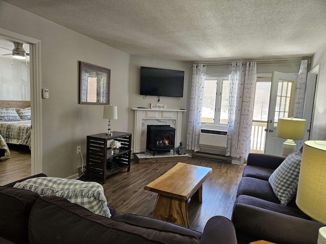 living area featuring cooling unit, a fireplace, a textured ceiling, and wood finished floors