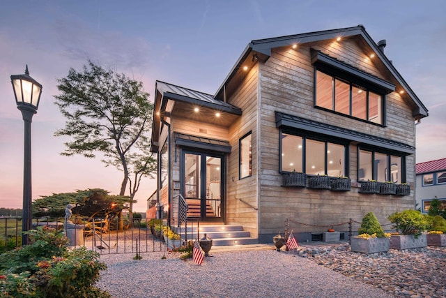 view of front of property with a standing seam roof, fence, and metal roof