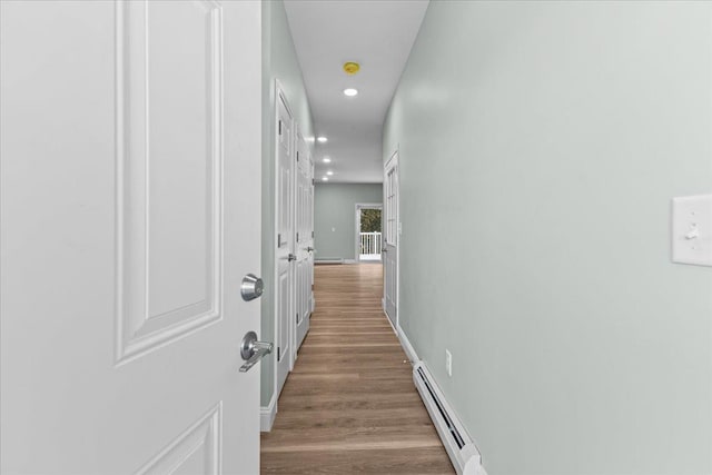 hall featuring recessed lighting, a baseboard radiator, wood finished floors, and baseboards