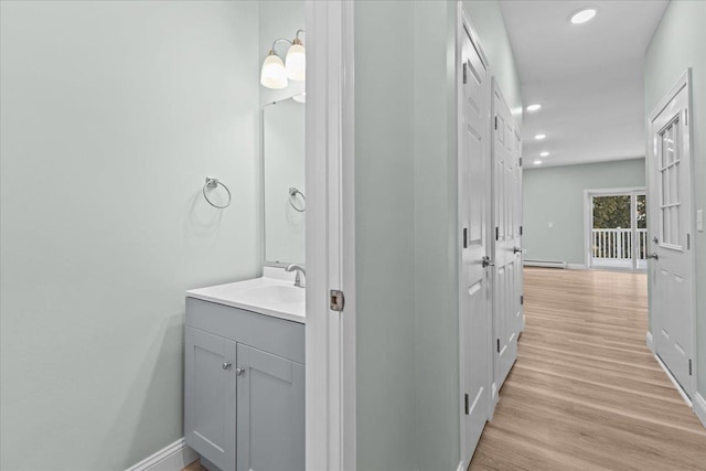 bathroom featuring recessed lighting, wood finished floors, a baseboard radiator, and baseboards