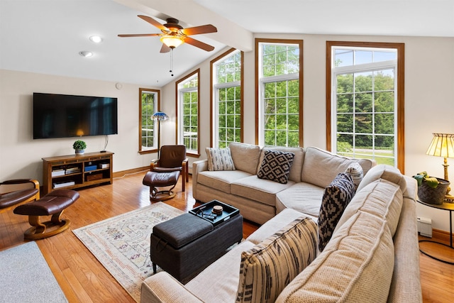 living area with vaulted ceiling with beams, a baseboard heating unit, a ceiling fan, baseboards, and hardwood / wood-style floors